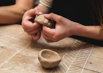 hands working and finishing sculpture with clay on wooden table