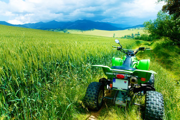 Green Quad in landscape on road in field. © jozefklopacka