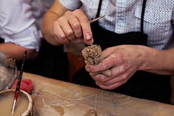 hands working and finishing sculpture with clay on wooden table