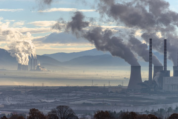 Power plant with smoking chimneys. Mountains in the background.. - 136311245