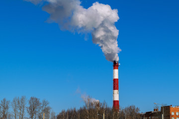 High pipe thermal power plant on the background of blue sky, fog