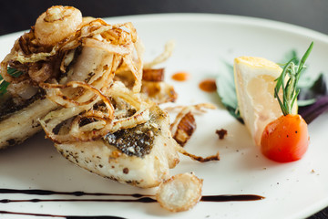 Walleye on the grill with onions on a white plate on a wooden table