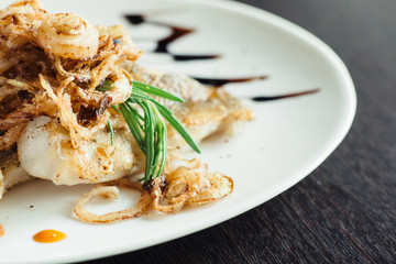 Walleye on the grill with onions on a white plate on a wooden table