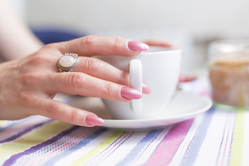 cup of coffee and beautiful woman hand with long nails on finger