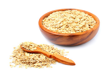 Oat flakes in a wooden bowl and wooden spoon isolated.