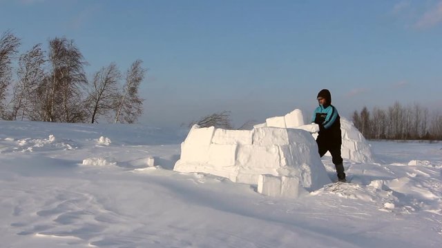 Man building an igloo  in a blizzard in the winter
