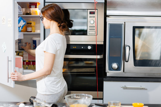 Housewife opening door of fridge to take food products