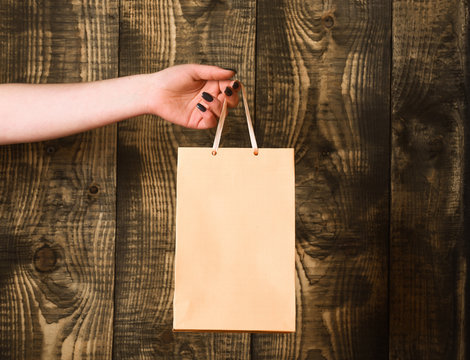light orange shopping bag in female hand on wooden background