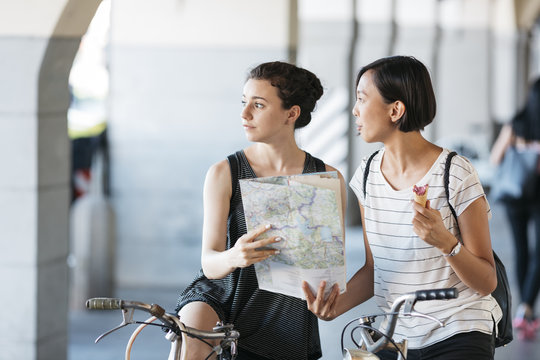 Italy, two young tourists with bicycles and map