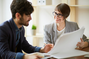 Portrait of two successful business people communicating, making final decisions  discussing working plans and documentation in modern office