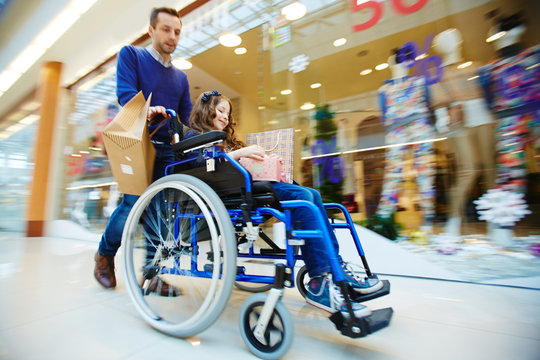 Man and his daughter in wheelchair shopping together during sale