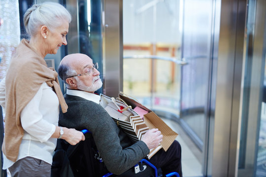 Senior spouses entering modern shopping-center