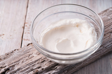 Natural yogurt in the glass bowl on the white wooden background horizontal