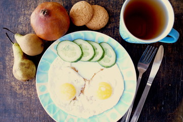 Healthy breakfast, fried eggs, cucumber, fruit, tea