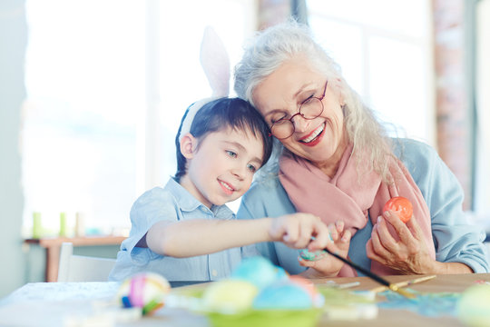 Grandmother and grandson painting Easter eggs together