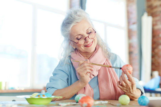 Aged female painting Easter eggs for holiday