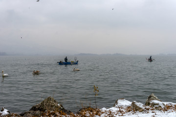 Fishermen at the magnificent lake of Kastoria, Greece during a w - 136320842