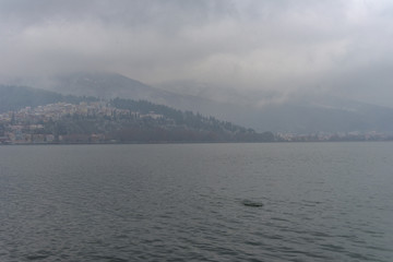 Foggy winter scenery at the lake of Kastoria Greece, during a he