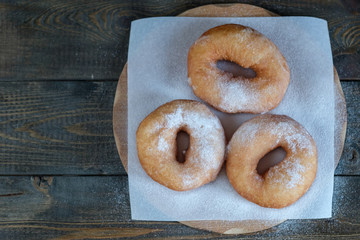 donuts sprinkled with powdered sugar lie on the board