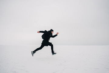 a young man in a black backpack and traveling on the frozen pond