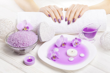 Fototapeta na wymiar beautiful pink manicure with orchid and towel on the white wooden table. spa
