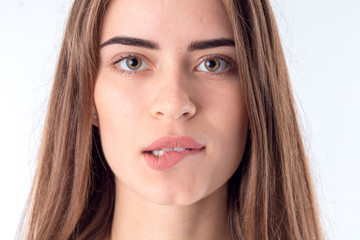 Portrait of a young girl who looks straight and bitten lip close-up