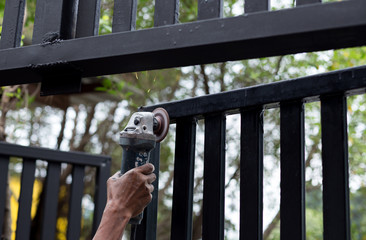 Hand holding steel cutting grinder working on metal door