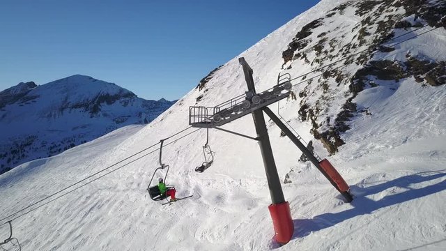 4k footage, aerial drone point of view skier going up with ski lift in winter mountains on sunny day
