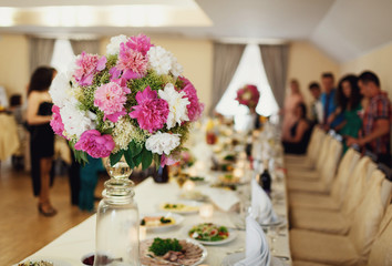 decor with bouquets of peonies on the table guests