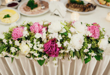 decor with bouquets of peonies on the table newlyweds