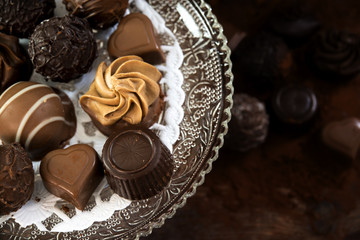 chocolate pralines on an étagère of glass, dark background
