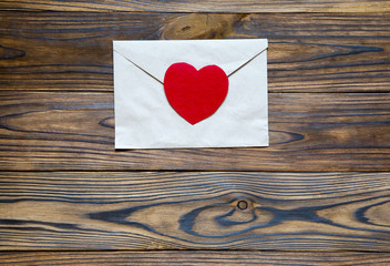 Love letter. Beautiful brown letter with red heart on wooden bac