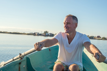 Happy man is rowing on a small boat