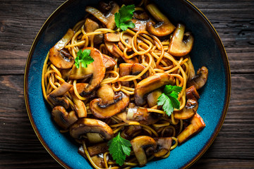 Closeup of pasta with mushrooms and parsley in blue bowl