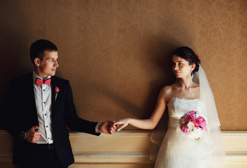 beautiful couple near a wall looking at each other and holding h