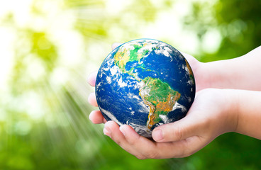 Child holding planet in hands against spring green background. Ecology concept. Earth day....
