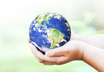 Child holding planet in hands against spring green background. Ecology concept. Earth day. environment concept. Elements of this image furnished by NASA.