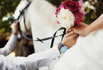 groom holds the hand of bride on horse