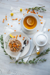 Serving table for breakfast: tea with lemon, granola and tea pot.