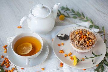 Serving table for breakfast: tea with lemon, granola and tea pot.