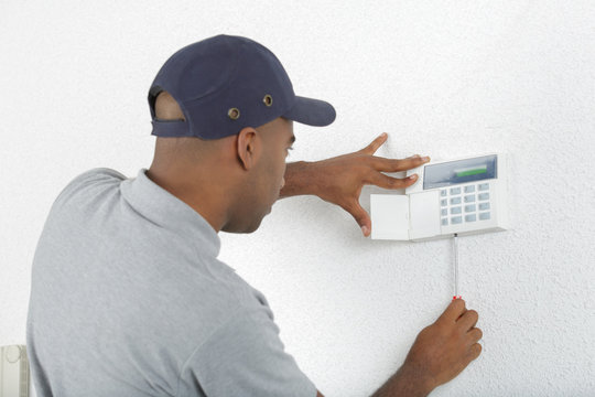 Workman fitting alarm key pad to wall