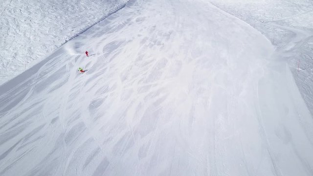 4k footage, two skiers skiing on ski slope drone point of view

