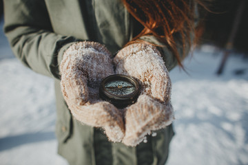Girl in hands with mittens holding an old compass. In winter for