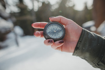 Naklejka premium Female hand holding old compass. In winter forest