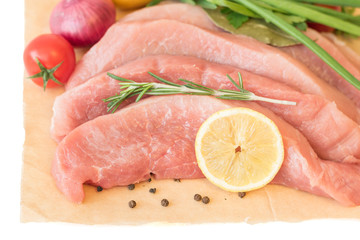 Sliced pork with vegetables and spices on paper.