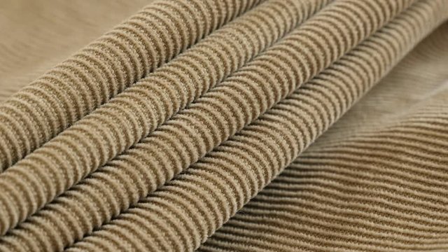 Cotton corduroy pattern gathers close-up slow pan 4K 2160p 30fps UltraHD footage - Modern brown velvet fabric pants tufted parallel cords 3840X2160 UHD panning video 