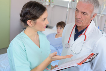 Doctor and nurse in discussion at patient's bedside