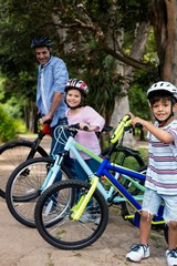 Fototapeta premium Father and children standing with bicycle in park