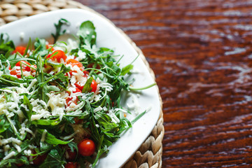 Fresh salad with tomato, ruccola on kitchen table.
