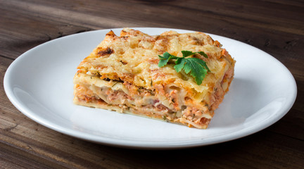 Close-up of a traditional lasagna topped with parskey leafs served on a white plate